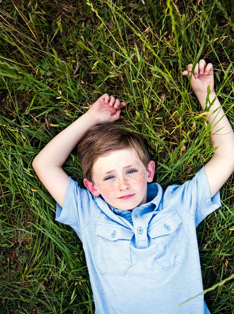 a-boy-in-a-blue-shirt-lying-on-his-back-on-grass